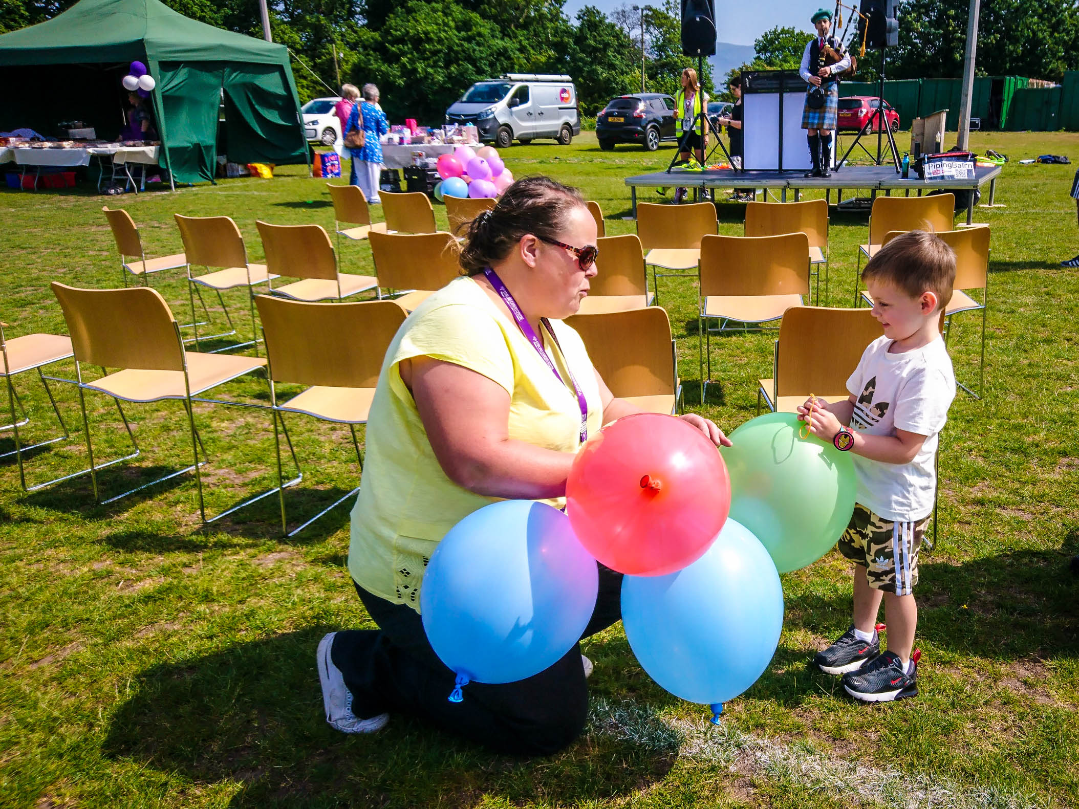 Female staff member handing out brightly coloured balloons to a young boy.