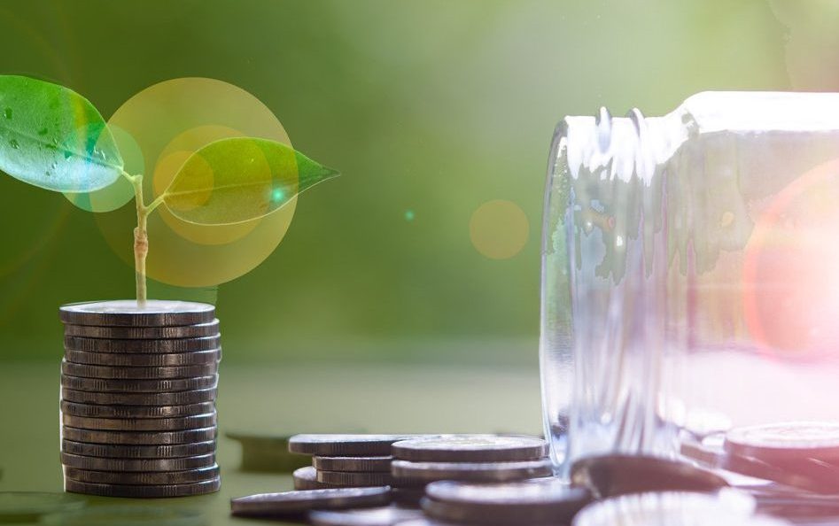Plants growing on coins and many coins from jar glass with green bokeh background