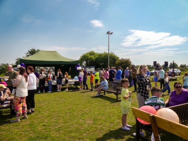 Crowds of people attending an open air event on a sunny day, with a tent serving food. Carers Week Fun
