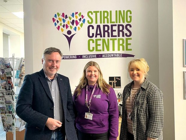 Three people standing in front of a Stirling Carers Centre sign. Alyn Smith and two staff members Alyn Smith MP coming along to talk